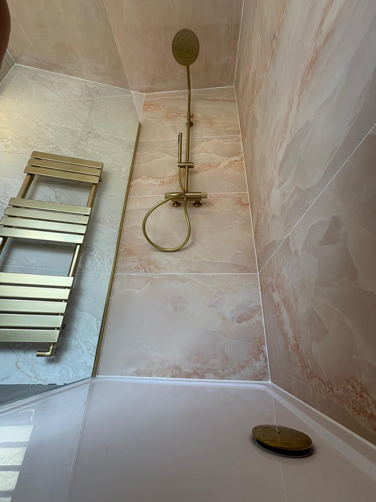 Brass rainfall shower and heated towel rail in a marble-effect shower