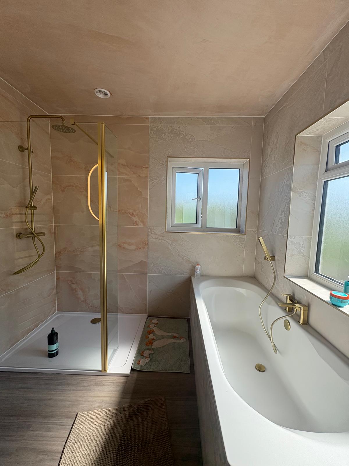 Finished bathroom with marble-effect tiles, a brass shower and a white bath