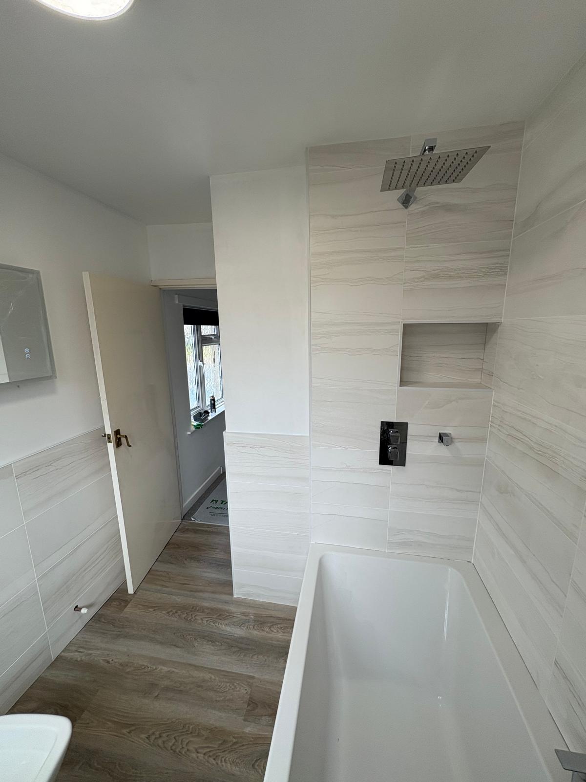 White marble-effect bathroom with a rainfall shower over the bath